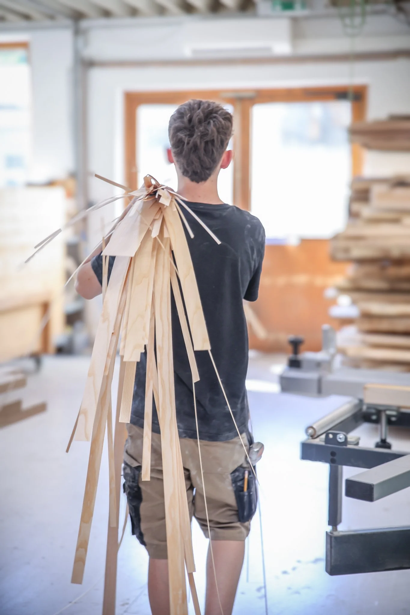Ein Mitarbeiter trägt Holzleisten durch die eigene Werkstatt der Tischlerei Zach.