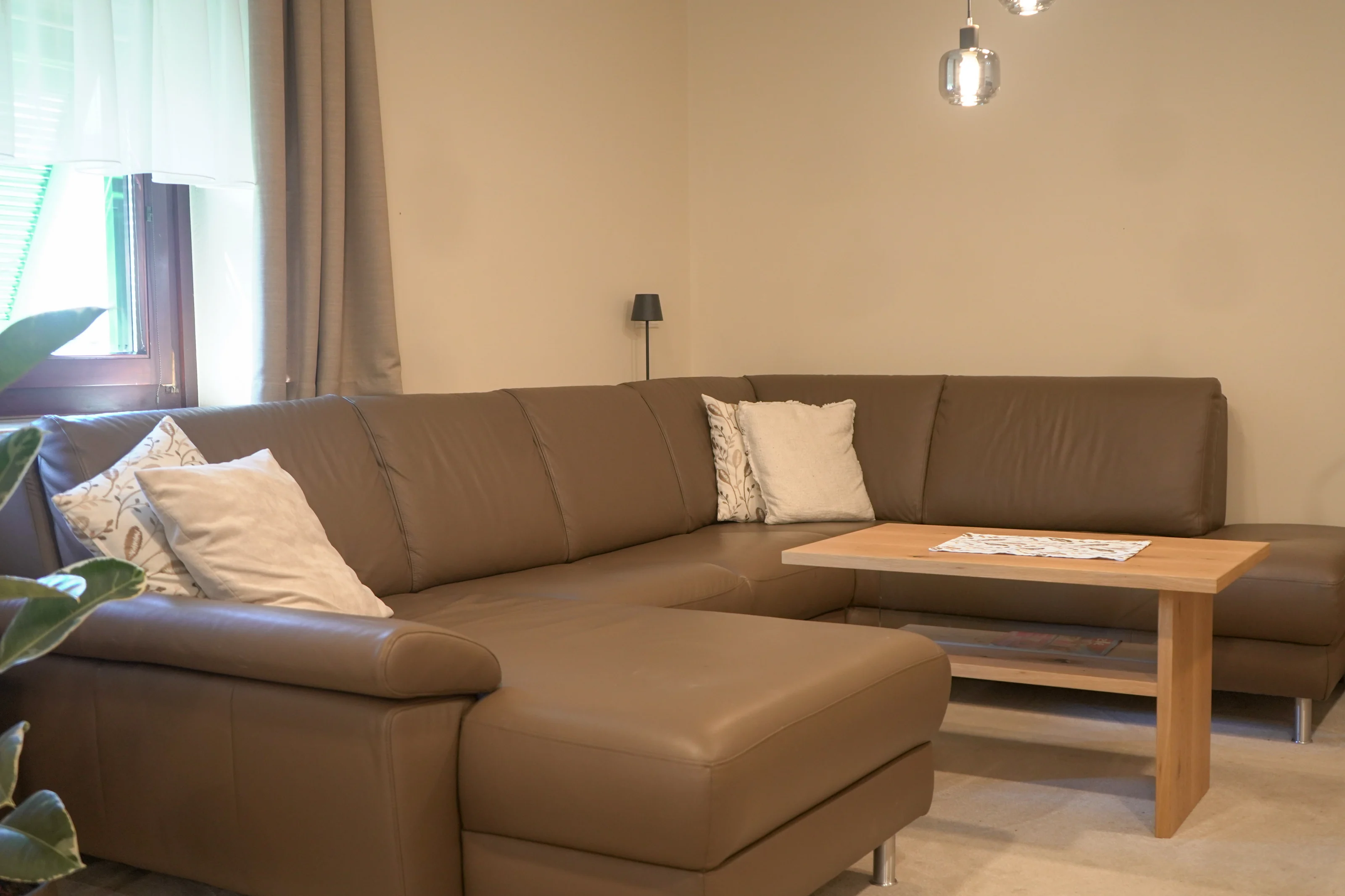 Sofaecke mit niedrigem Holztisch und passenden Holzablagen.
