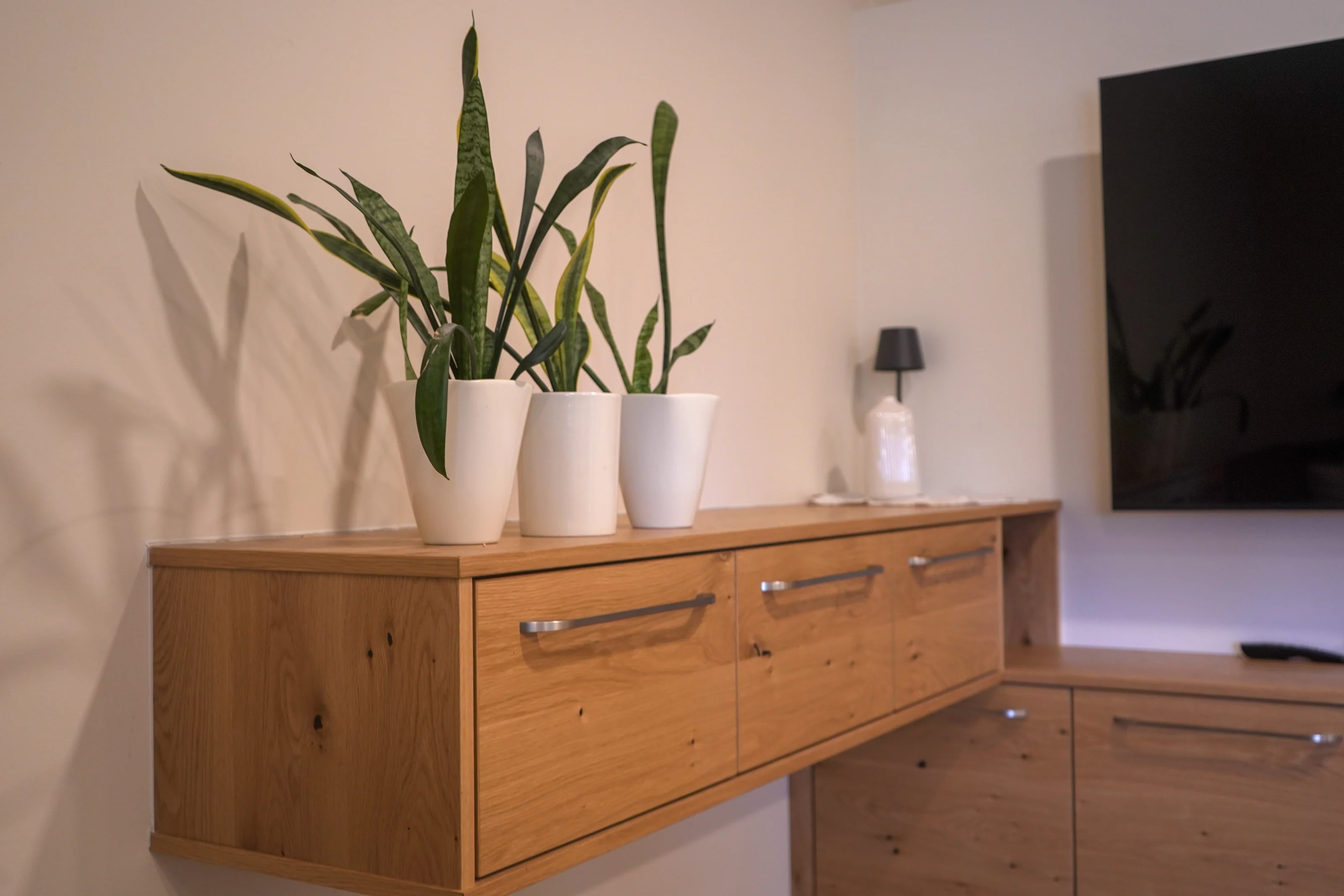 Holzkommode im Wohnzimmer mit Pflanzen und Vasen.